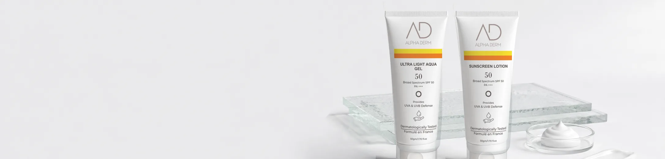 Ultra Light Aqua Gel and Sunscreen Lotion tubes on glass slabs beside a dish of cream